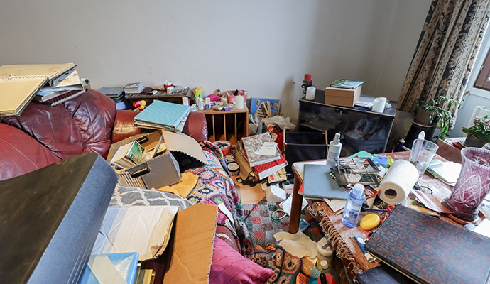 A cluttered residential room with extreme hoarding conditions
