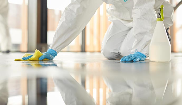 A person with hazmat suits wiping the tile surface