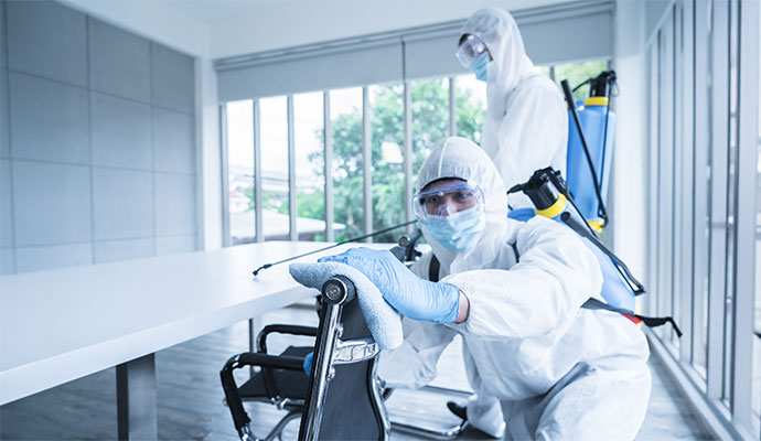 Commercial office disinfection service A team in HAZMAT suits disinfecting a modern office.