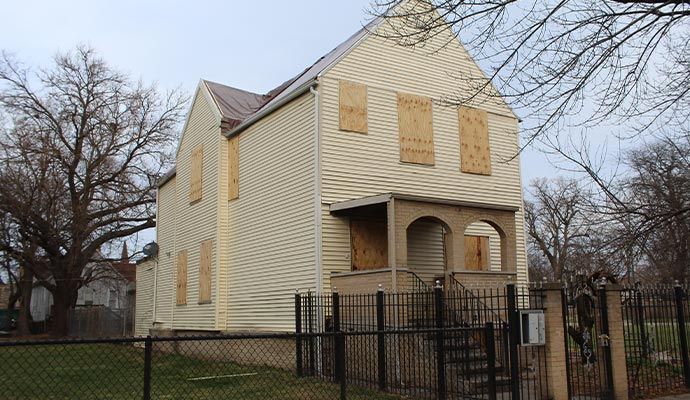 Boarded windows and door of house House exterior with all windows and main door covered with wooden boards.