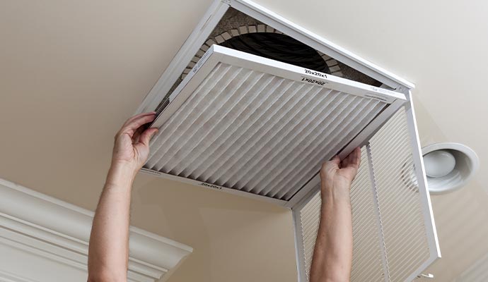 Person replacing ceiling vent air filter