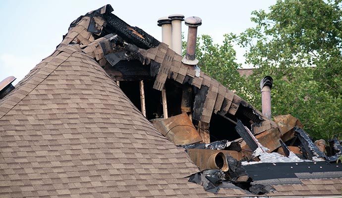 Severely fire-damaged house roof with charred shingles