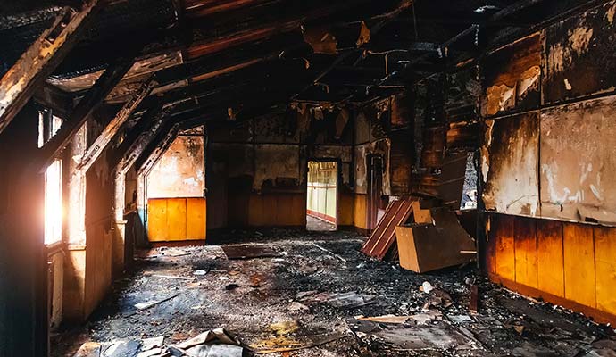 Interior of a commercial space severely damaged by fire with charred walls and debris.