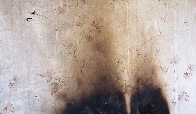 Interior wall covered with smoke stains and discoloration after a fire incident.