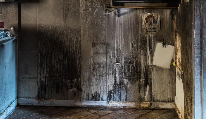 Drywall showing visible smoke and soot damage from a house fire.
