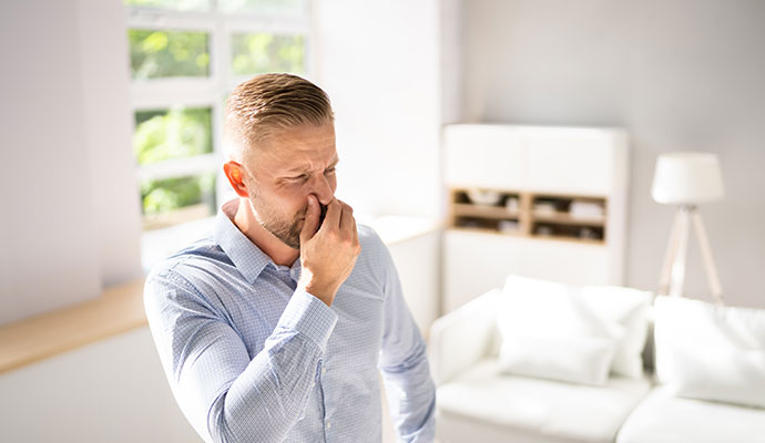 Man pinching his nose from a musty smell