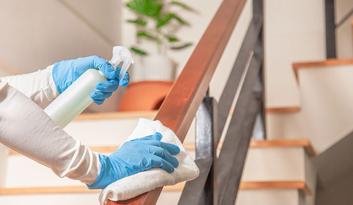 A person sanitizing stair railing