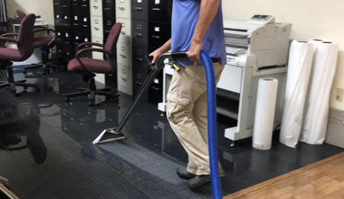 Professional worker cleaning water damaged office room floor