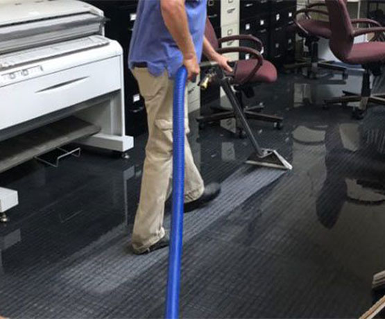 Professional worker extracting water from carpet Professional worker extracting water from carpet