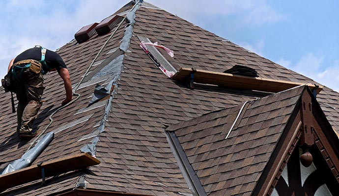 A worker is repairing a damaged leaky roof.