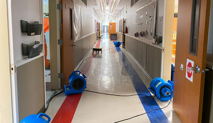 Drying equipment in a school hallway after a water damage event.