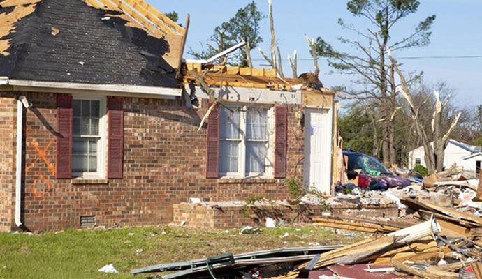 Storm-damaged brick house with debris