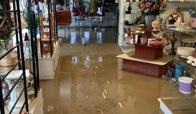 Retail store interior with standing water and damaged flooring after flood.