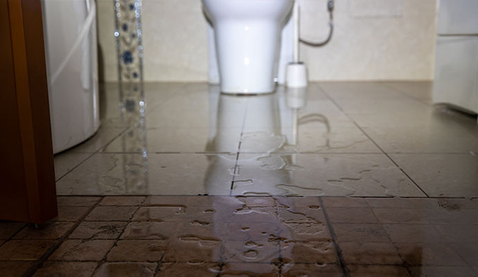 Water pooling across a tiled bathroom floor