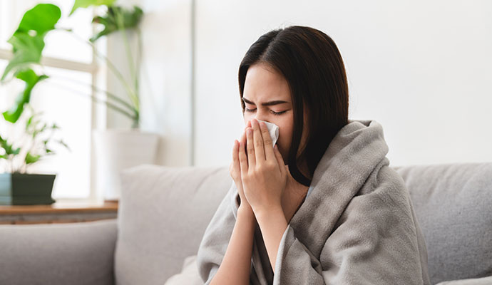 Woman blowing her nose on a couch
